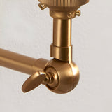 Close-up of the Endon Danemere wall light's brushed aged brass adjustable knuckle joint and slim arm against a plain white wall.