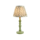 Endon Aldworth Leaf table lamp with turned green wooden spindle base and pleated leaf-print fabric shade in green and cream, on a white background.