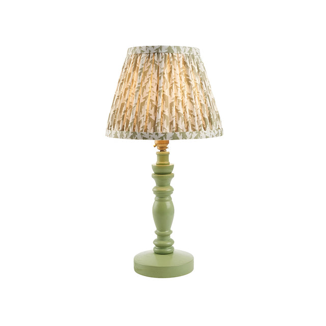 Endon Aldworth Leaf table lamp with turned green wooden spindle base and pleated leaf-print fabric shade in green and cream, on a white background.