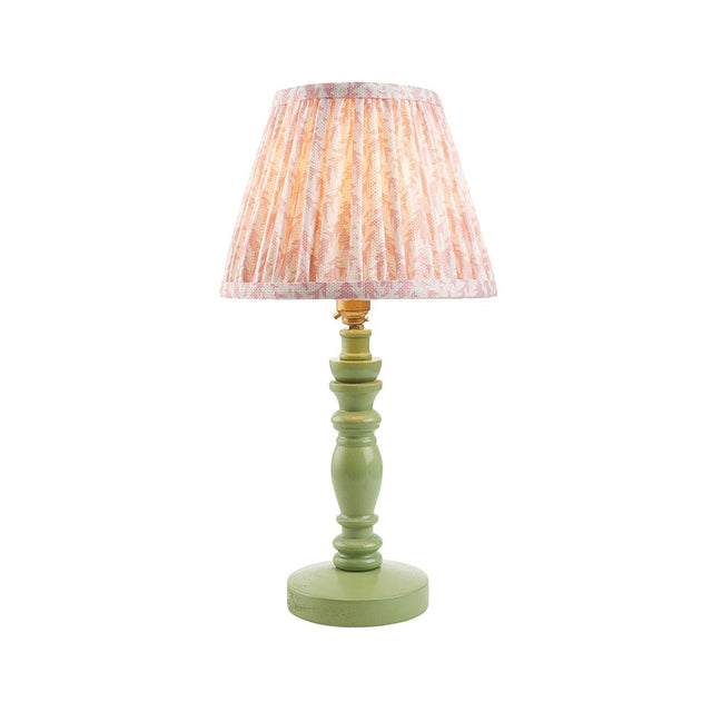 Endon Aldworth Leaf table lamp with green turned wood spindle base, brass B22 lampholder and pleated pink leaf-print fabric shade on a white background.