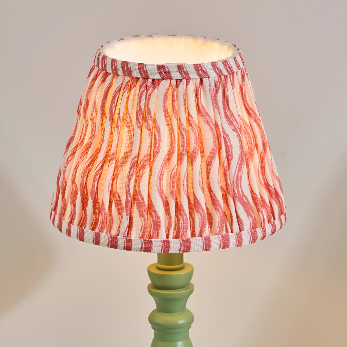 Endon Aldworth Ripple table lamp with a pleated coral pink ripple-print shade on a green turned wooden spindle base.