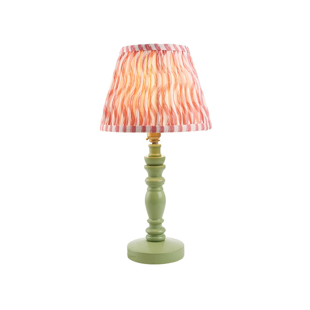 Endon Aldworth Ripple table lamp with green turned wood spindle base, brass lampholder and pleated coral pink ripple-print shade, on white.
