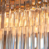 Close-up of the Bevstead 4 Light Linear Pendant in brushed brass, showing clear faceted glass rods catching warm light.