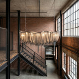 Mireya 8 Light Chain Veil Chandelier in nickel suspended from twin square-link chains in an industrial loft with exposed brick and a metal staircase.