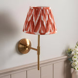 Endon Castleigh Zigzag wall light with brushed aged brass T-shaped arm and stepped backplate, topped by a red and white pleated tapered shade.