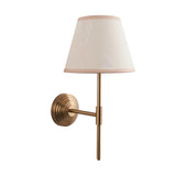 Castleigh Ivy wall light in brushed brass with stepped back plate, adjustable T-shaped arm, and tapered vintage white fabric shade with almond trim.