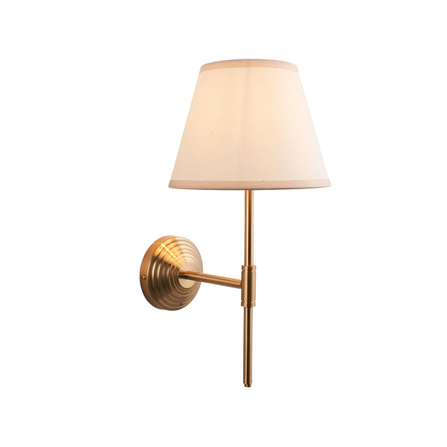 Castleigh Ivy wall light with brass stepped back plate, T-shaped arm and beige tapered fabric shade, shown on a plain white background.
