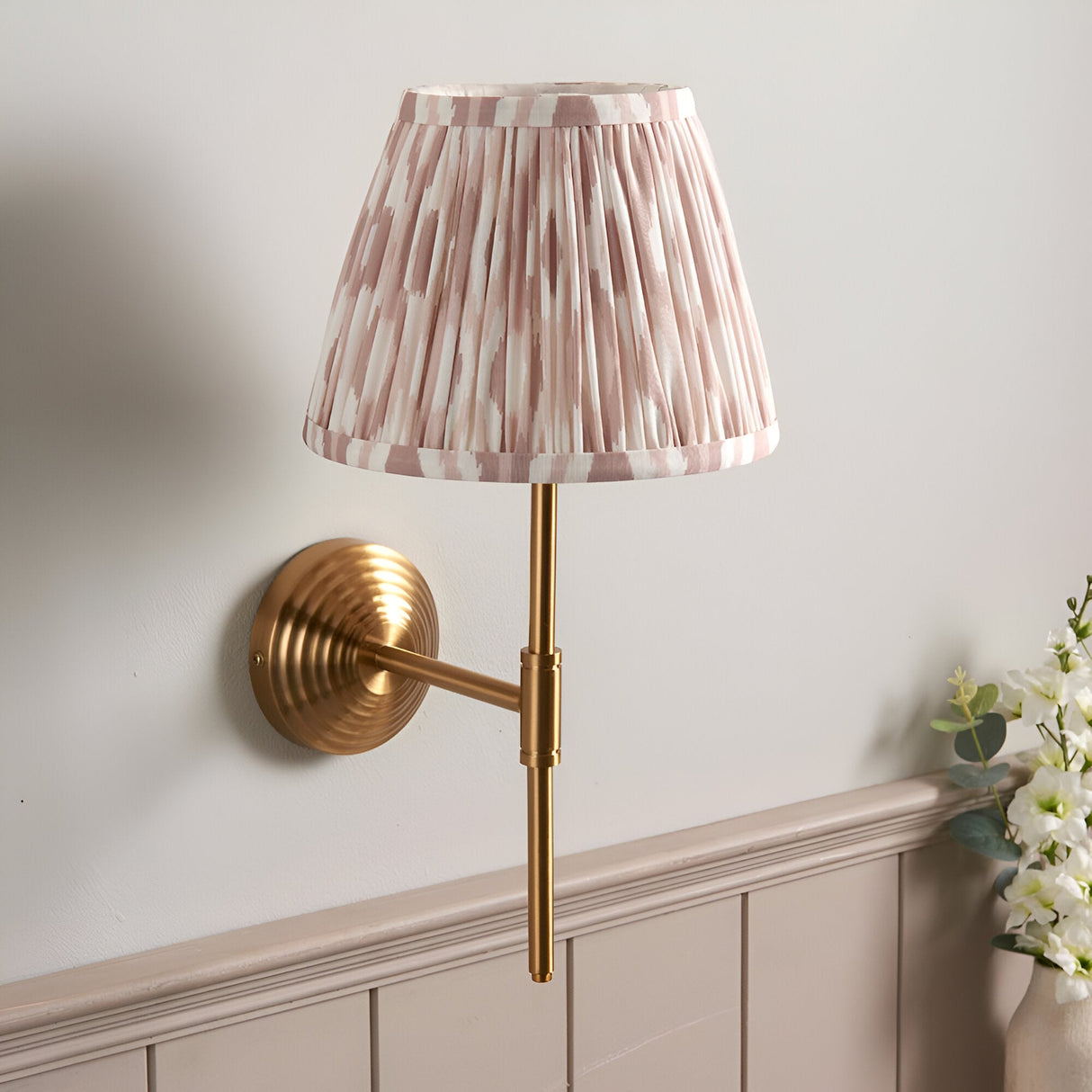 Endon Castleigh wall light with brushed aged brass stepped backplate, adjustable T-arm and pleated pink and cream Ikat tapered shade.