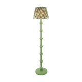 Bevbury turned wood floor lamp in green with a pleated zigzag-patterned shade in grey, brass and green tones, on a plain white background.