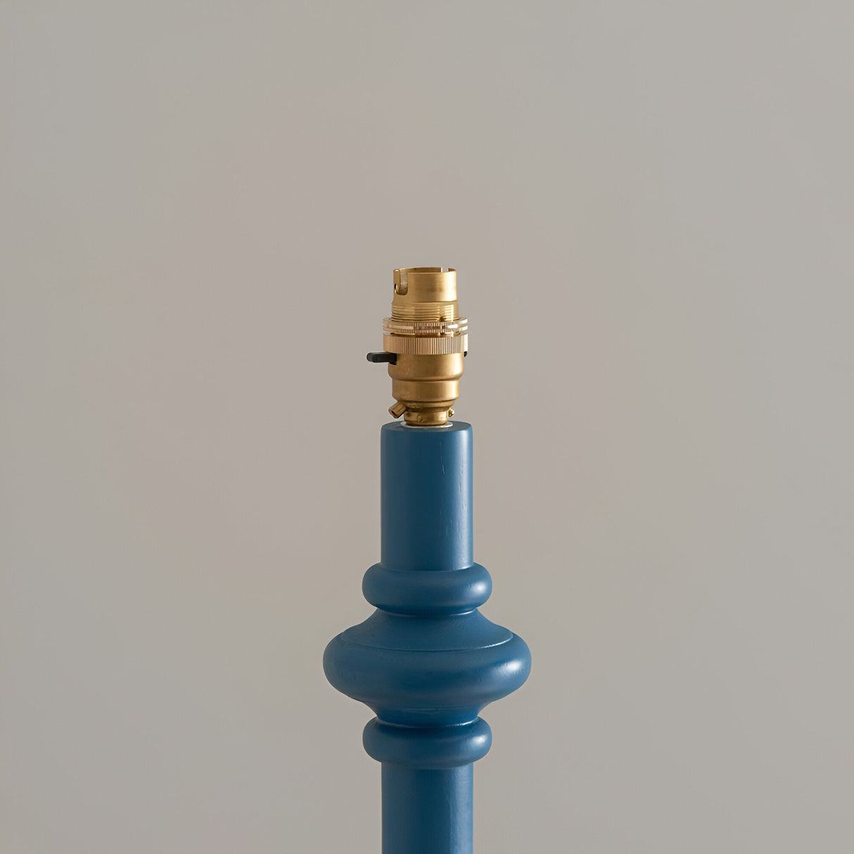 Close-up of the Endon Bevbury floor lamp's blue turned wood spindle base with ringed detailing and switched brass B22 lamp holder on a neutral background.