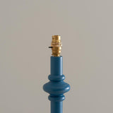 Close-up of Endon Bevbury Ripple floor lamp's blue turned wood spindle base with decorative bulge and switched brass B22 lamp holder on a light background.