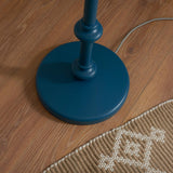 Close-up of the Endon Bevbury Ripple floor lamp's marlin blue turned wood spindle base on wood flooring, beside a woven rug and grey braided flex.