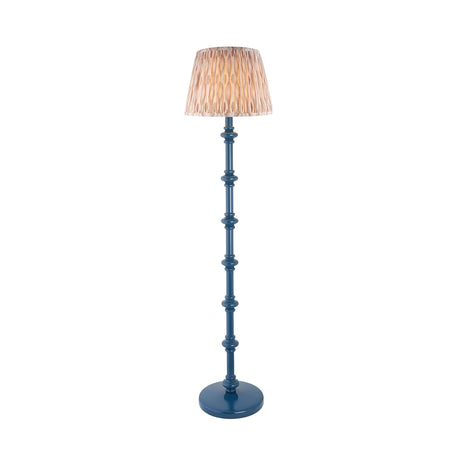Endon Bevbury Ikat floor lamp with blue turned wood spindle base and pleated natural patterned faux silk shade on a plain white background.