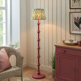 Endon Bevbury Zigzag floor lamp with pink turned wooden spindle base and green zigzag pleated shade, beside a wicker chair and pink sideboard.