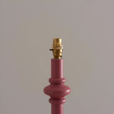 Close-up of the Endon Bevbury floor lamp's pink clay turned wood spindle base with switched brass B22 lamp holder on a neutral background.