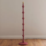 Endon Bevbury floor lamp base in pink turned wood with stacked spindle detailing and brass B22 holder, shown against a neutral wall on wood flooring.