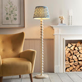 Endon Brenleigh Ripple floor lamp with white stacked sphere base and blue patterned pleated shade, beside a yellow armchair and log-filled fireplace.