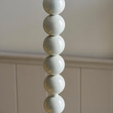 Close-up of the Endon Brenleigh Ripple floor lamp base showing stacked glossy white spheres against a neutral panelled wall.