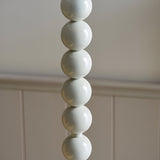 Endon Brenleigh Ripple floor lamp base close-up showing stacked glossy white spheres against a panelled wall.