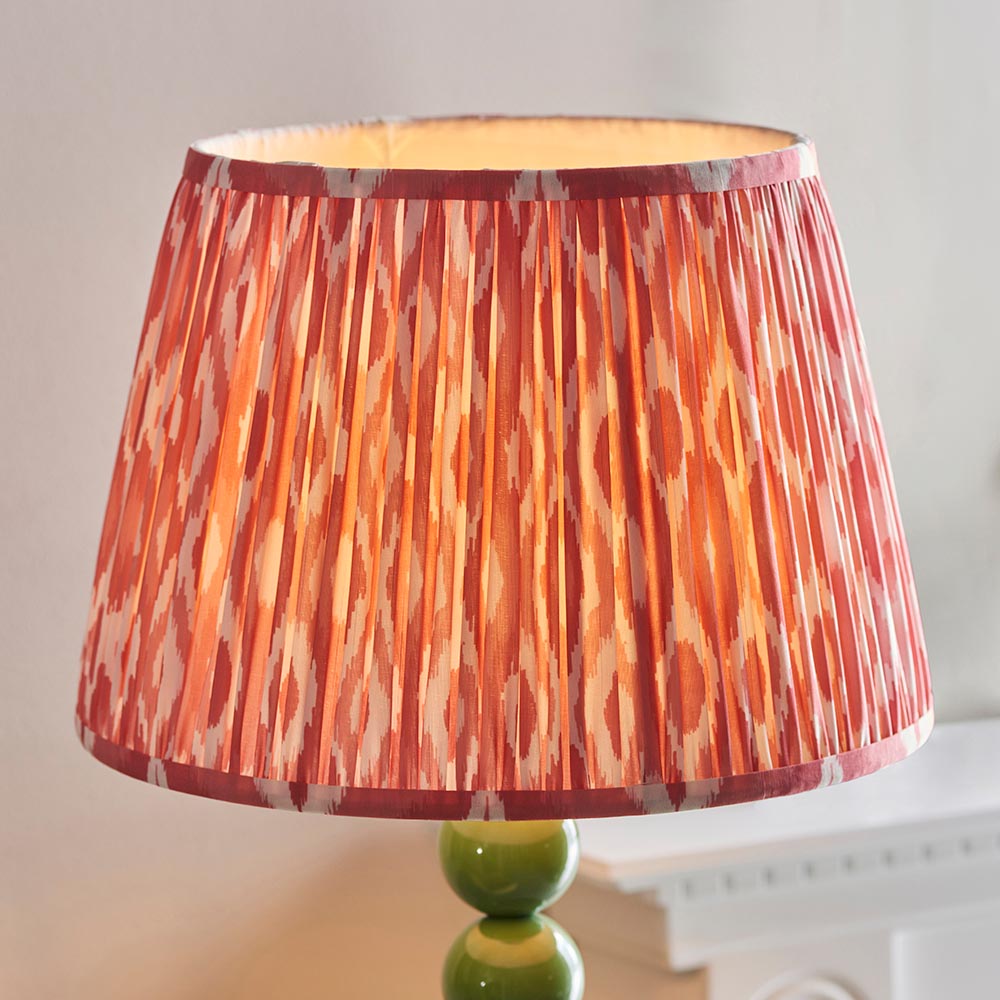 Brenleigh Ikat Floor Lamp with pleated pink and orange patterned fabric drum shade on a stacked green gloss sphere base, shown against a light background.