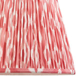 Close-up of the Brenleigh Ikat floor lamp's pleated fabric shade in pink and white ikat pattern with a taped edge trim, shown on a white background.