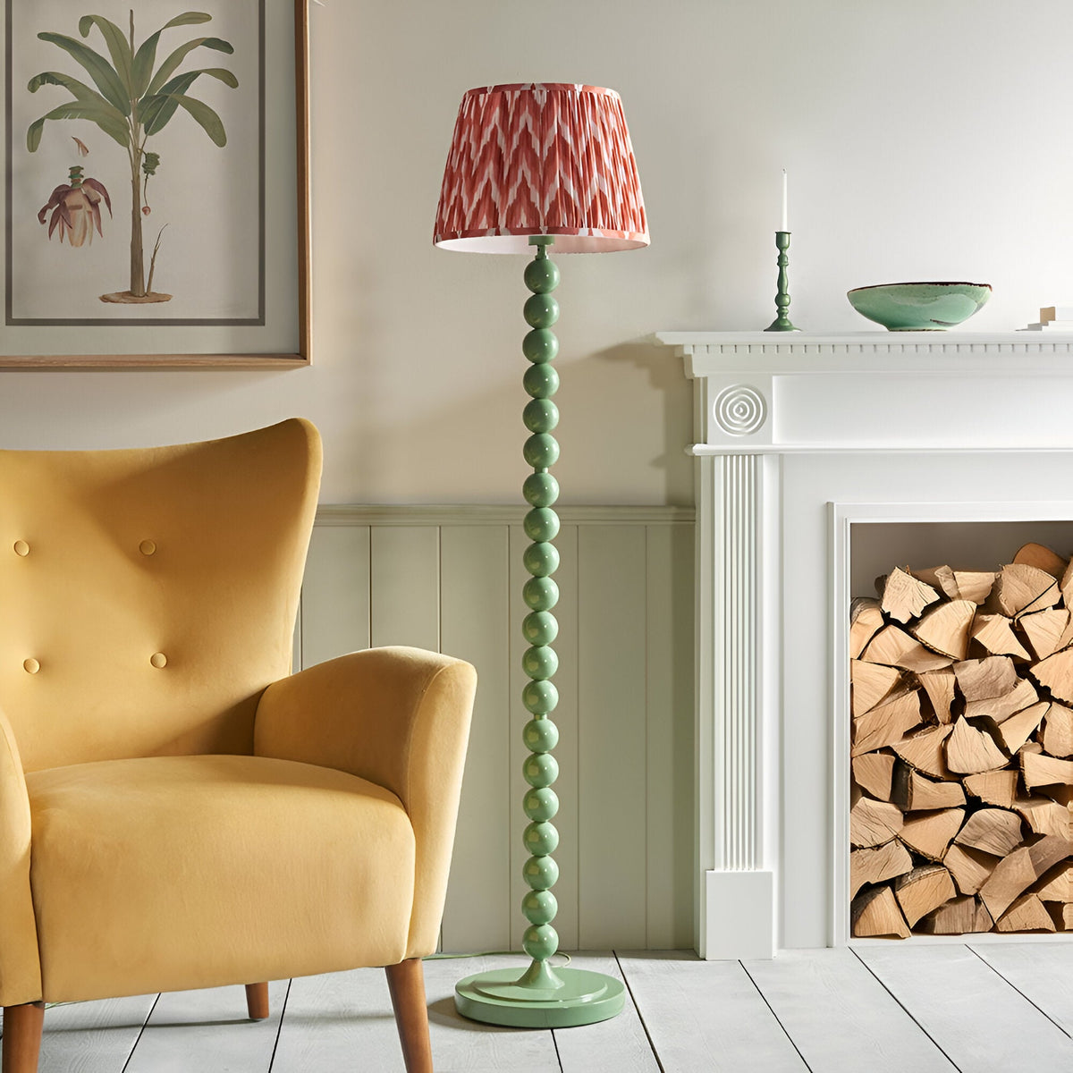Brenleigh Zigzag Floor Lamp in green, featuring a stacked sphere base and pleated coral zigzag-print shade, shown beside a fireplace in a living room.