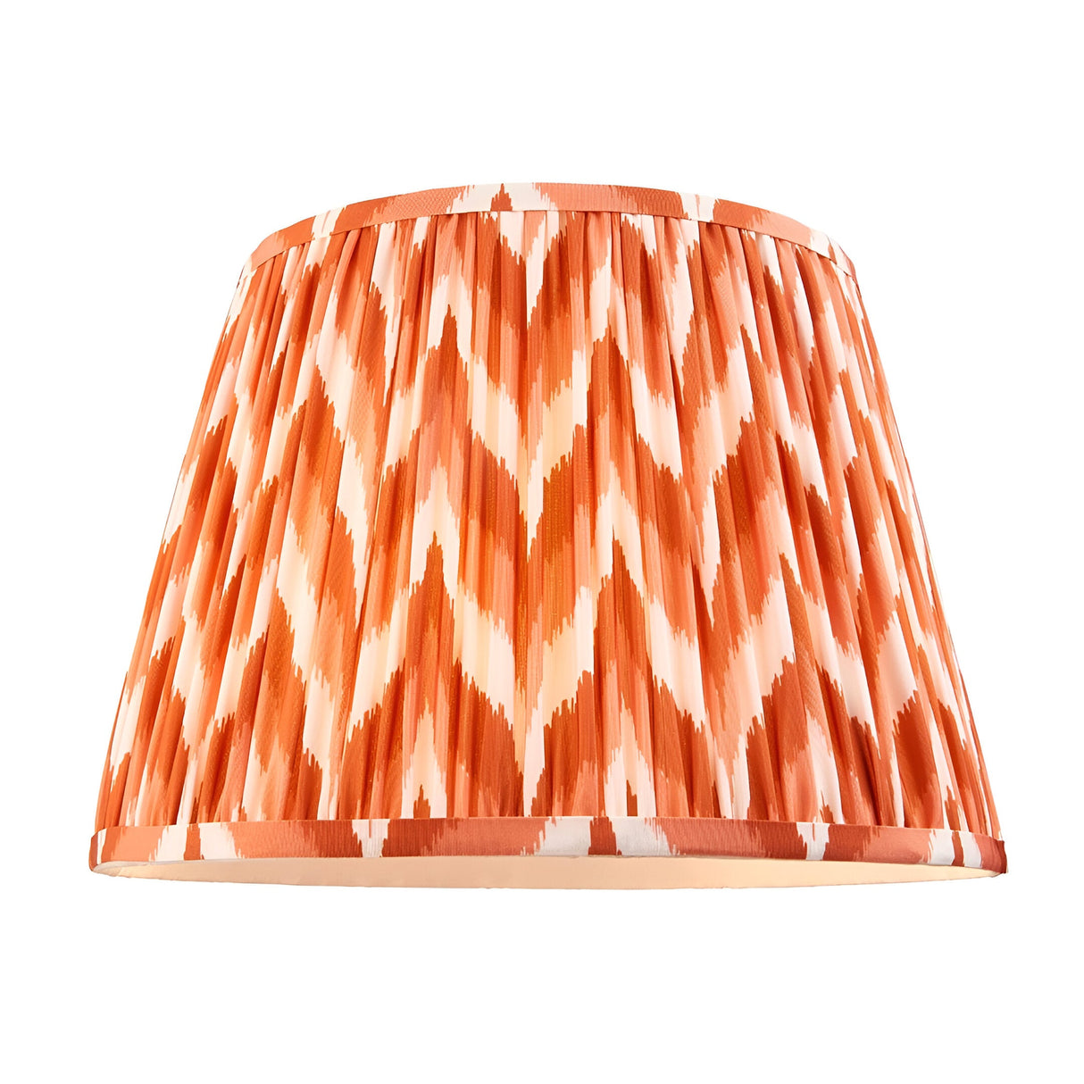 Zigzag pleated fabric lamp shade in orange and cream chevron pattern, tapered drum shape with taped edges, shown on a plain white background.