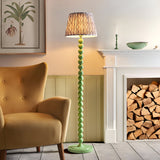 Endon Brenleigh floor lamp with stacked green sphere base and grey Ikat pleated shade, beside a mustard armchair and white fireplace with logs.