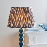 Brenleigh Zigzag Floor Lamp with stacked blue gloss sphere base and pleated grey zigzag-patterned fabric shade, shown beside a white fireplace mantel.
