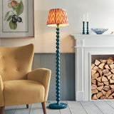 Endon Brenleigh stacked sphere floor lamp in glossy marlin blue with a pleated Zigzag shade, beside a mustard armchair and white fireplace with logs.