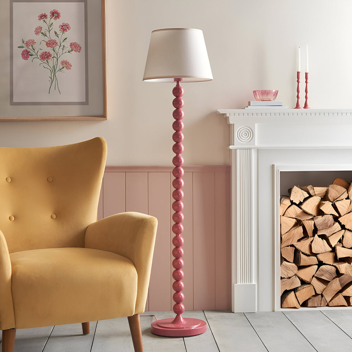 Endon Brenleigh Ivy floor lamp with glossy pink stacked sphere base and white tapered shade, beside a yellow armchair and white fireplace with logs.
