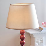 Endon Brenleigh Ivy floor lamp with glossy pink stacked sphere base and tapered vintage white fabric shade, beside a white mantel.