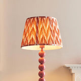 Brenleigh Zigzag Floor Lamp with pink stacked sphere base and orange chevron pleated fabric shade, shown against a light wall.