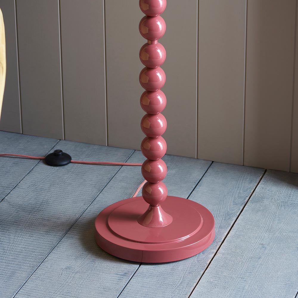 Brenleigh Zigzag Floor Lamp base close-up in pink gloss metal with stacked sphere stem on a round base, shown on grey floorboards.