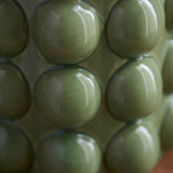 Close-up of the Endon Amberley Ripple table lamp's ceramic base showing rows of glossy olive green bobbles.