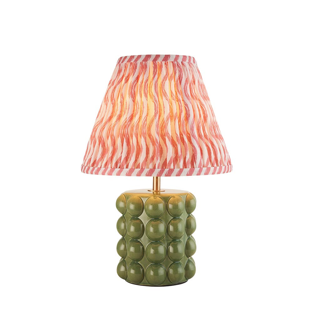 Amberley Ripple table lamp with a green ceramic bobble base, brass stem, and pink and orange wavy-pattern fabric shade on a white background.