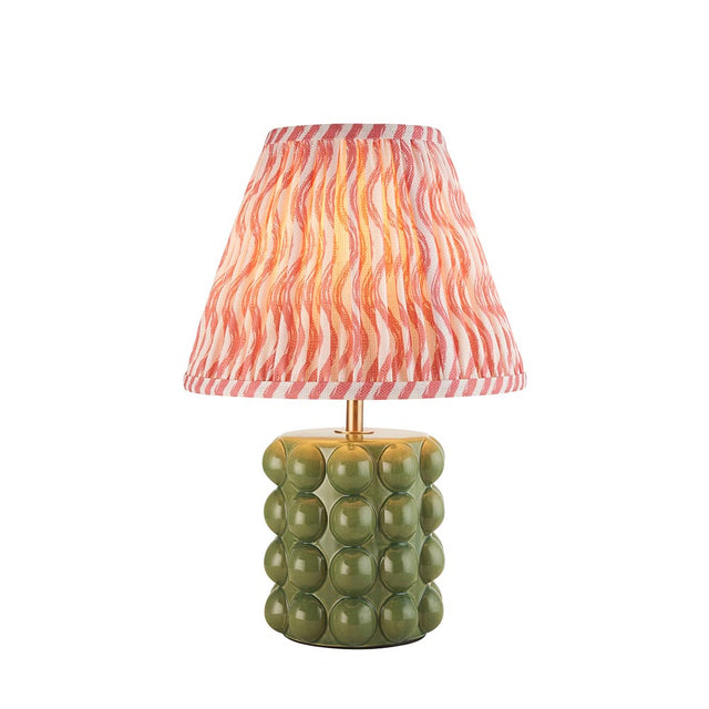 Amberley Ripple table lamp with a green ceramic bobble base, brass stem, and pink and orange wavy-pattern fabric shade on a white background.