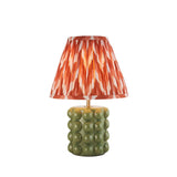 Endon Amberley table lamp with glossy olive green bobble ceramic base, aged brass stem, and pleated apricot orange zigzag shade on a white background.