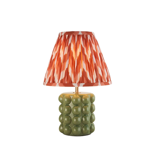 Endon Amberley table lamp with glossy olive green bobble ceramic base, aged brass stem, and pleated apricot orange zigzag shade on a white background.