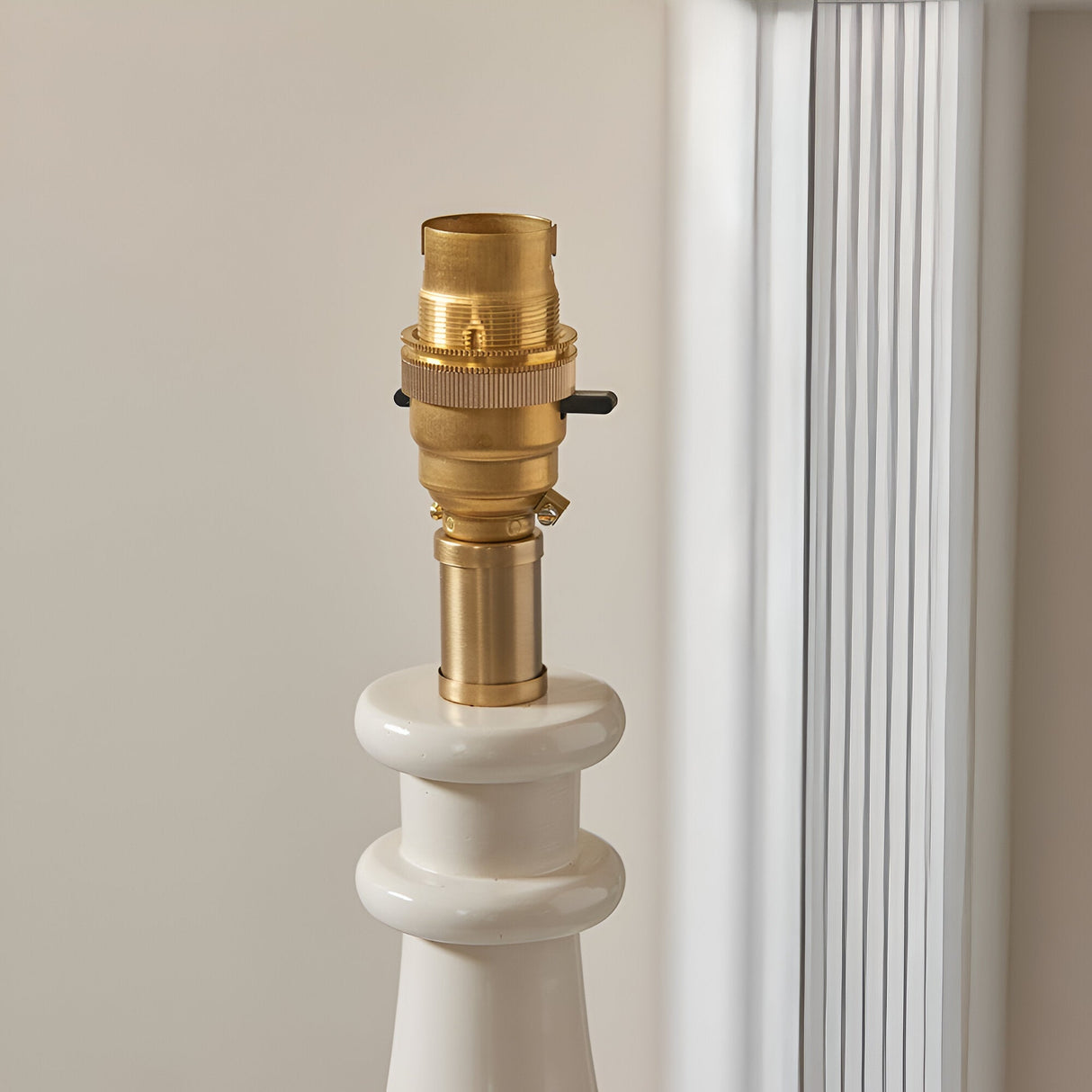 Close-up of Endon Carlworth Ikat Table Lamp II showing brass B22 bayonet lamp holder atop a white gloss turned resin spindle base.