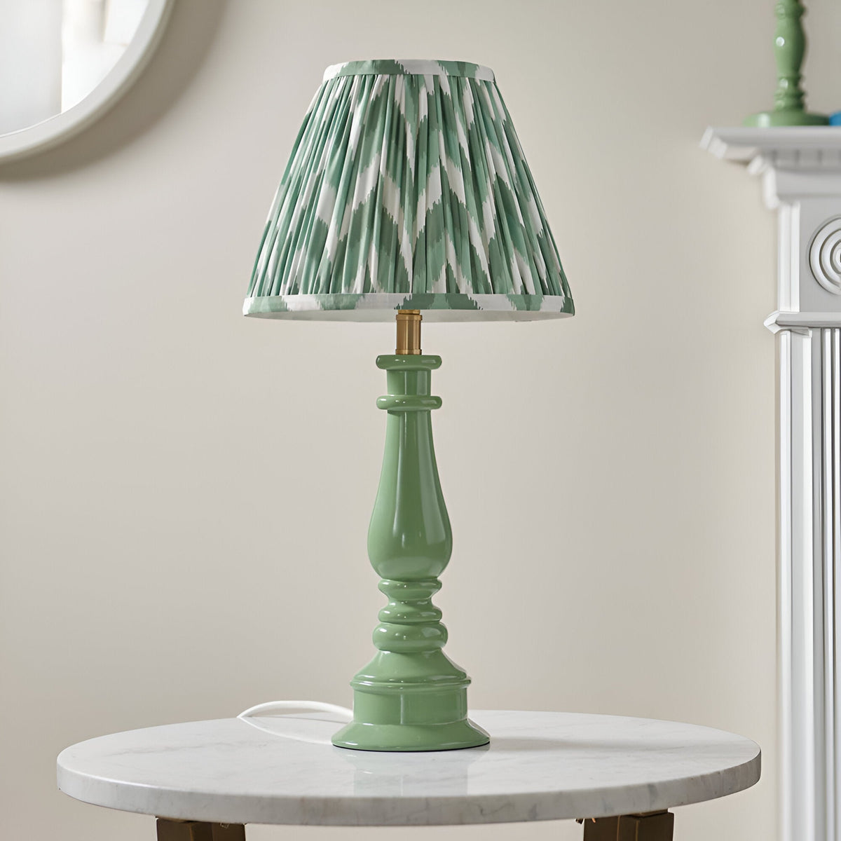 Carlworth Zigzag Table Lamp II in Cotswold Green with a spindle-style resin base and pleated chevron-print shade, shown on a marble side table.
