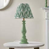 Carlworth Zigzag Table Lamp II in Cotswold Green with a spindle-style resin base and pleated chevron-print shade, shown on a marble side table.
