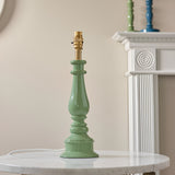 Carlworth Zigzag Table Lamp base in Cotswold Green resin with turned spindle column and brass fitting, shown shadeless on a marble table near a white mantel.