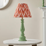 Carlworth Zigzag Table Lamp with a green spindle-style resin base and pleated apricot zigzag-print shade, shown on a marble side table.