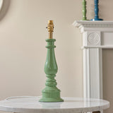 Carlworth Zigzag Table Lamp base in green resin with turned spindle shape and brass fitting, shown shadeless on a marble table near a white mantelpiece.
