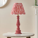 Endon Carlworth Ikat table lamp with pink clay gloss turned resin spindle base and pleated coral ikat faux silk shade, on a marble side table.