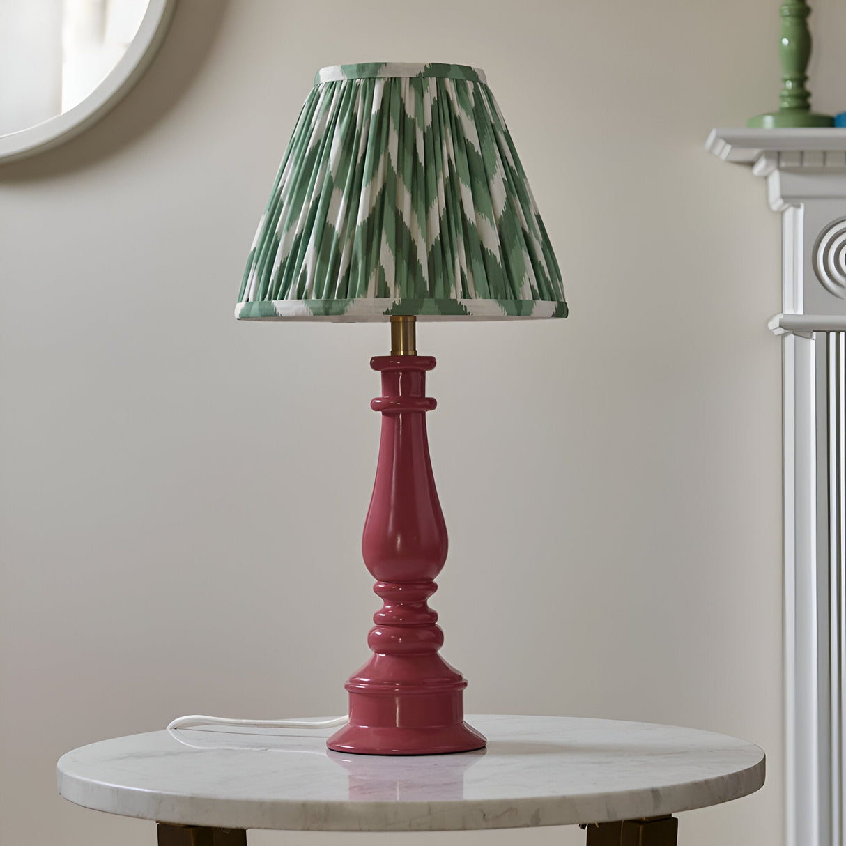 Carlworth Zigzag Table Lamp with pink clay resin spindle base and pleated green zigzag-print shade, shown on a marble side table.