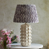 Amberley Ikat Table Lamp with textured white ceramic bobble base and pleated grey and silver Ikat print shade, shown on a marble side table.
