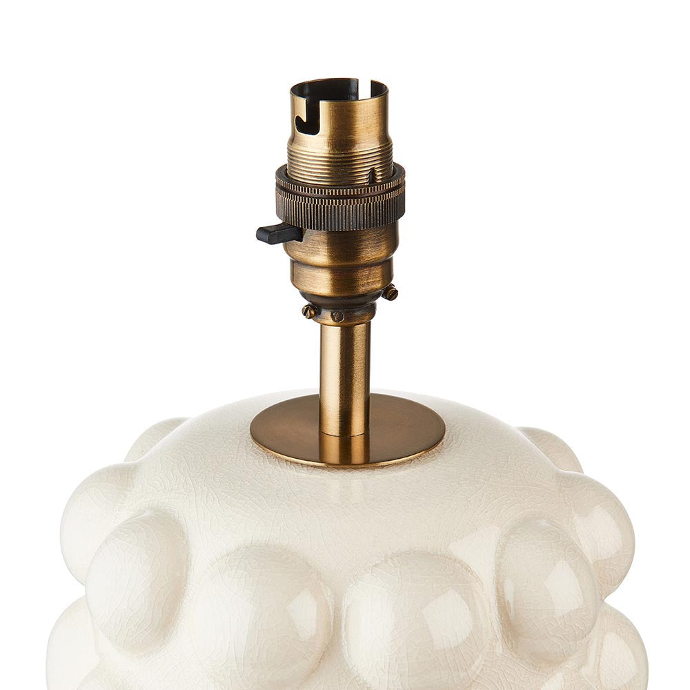 Close-up of the Endon Amberley Ikat table lamp's aged brass B22 switched holder and stem on a white ceramic bobble base.