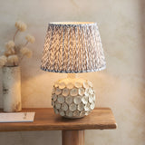 Ashbury Leaf Table Lamp with round textured ceramic base and pleated grey leaf-print fabric shade, styled on a wooden console table.